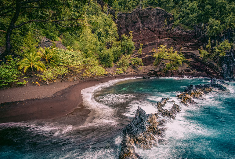 Water splashes beneath on Red Sand Beach in Maui, Hawaii. 